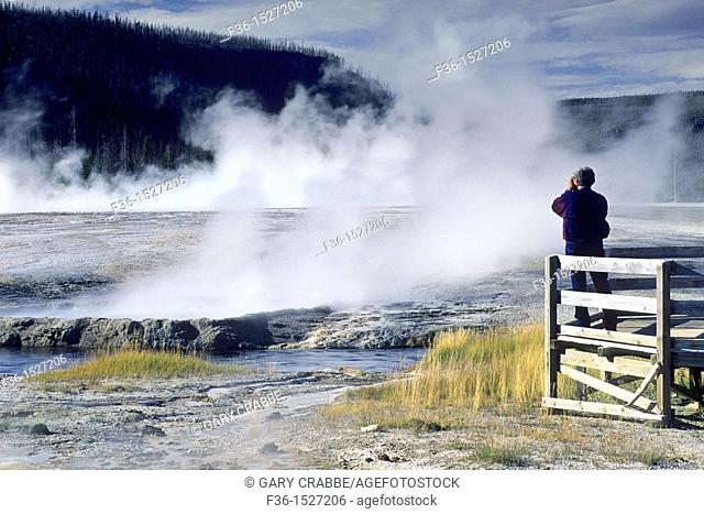 Tourist at boardwalk over look at Cliff Geyser, Black Sand Basin, Yellowstone National Park, WYOMING