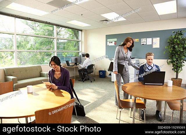 Diverse group of people in an open office area working on electronic devises