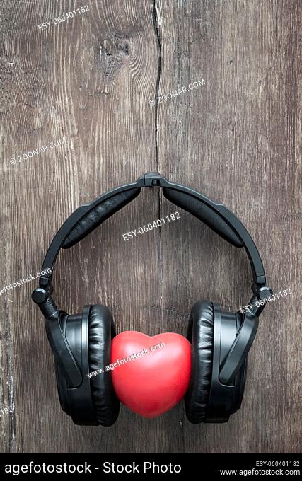 black headphones with red heart on rustic wooden background