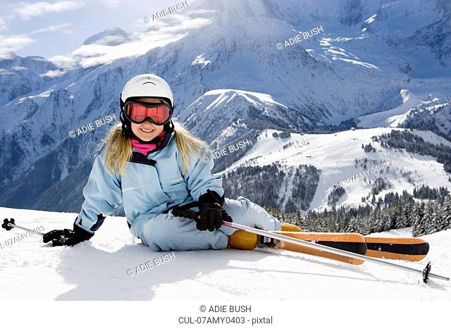 Girl with skis lying on the snow