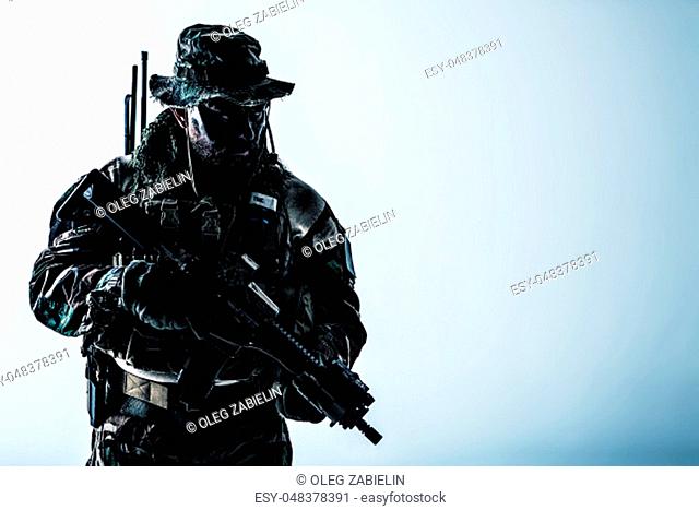 Special forces United States in Camouflage Uniforms studio shot. Holding weapons, wearing jungle hat, Shemagh scarf, painted face, he is ready to kill