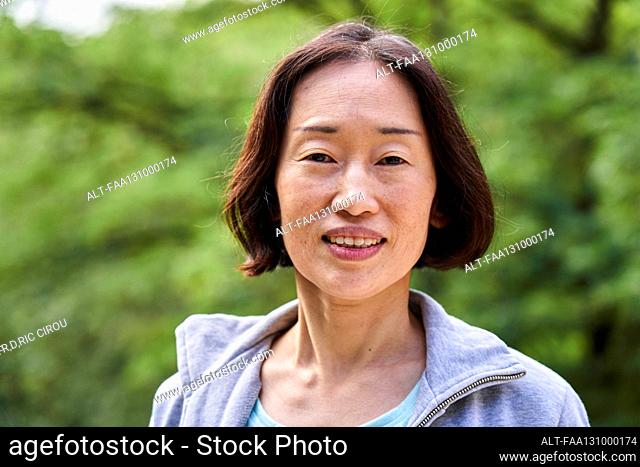 Senior Asian woman looking at the camera while standing outdoors