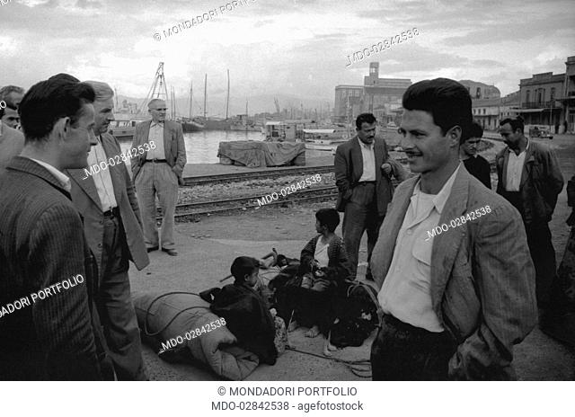 Men chatting in a harbour. Greece, November 1958