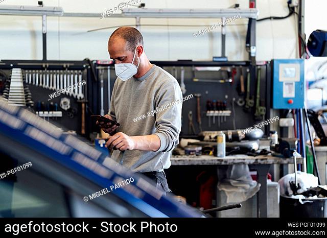 Mechanic using mobile phone in auto workshop