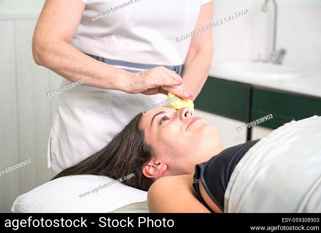 A beautician performs make-up removal from the client's face in a beauty salon. High quality photo
