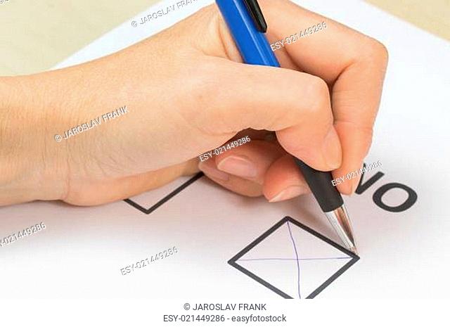 Female hand is holding a blue pen and filling NO in the white printed form