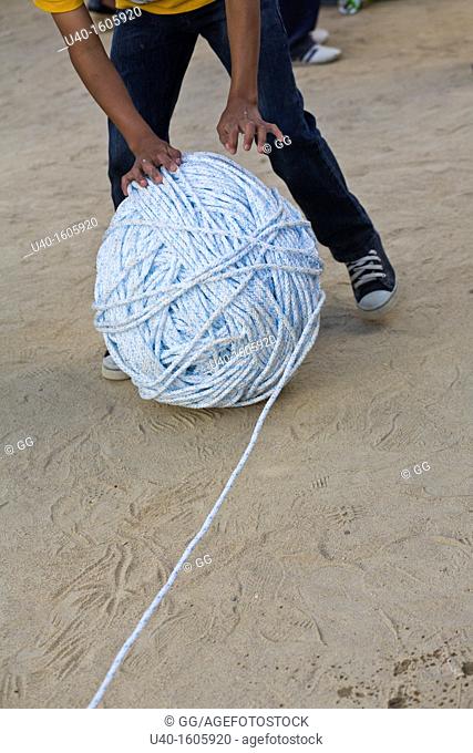 Boy rolling a giant ball of string