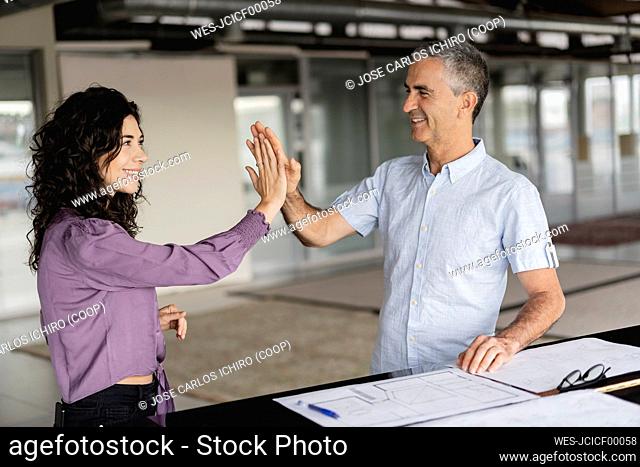 Business colleagues giving high-five to each other at office