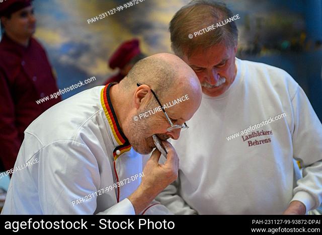 27 November 2023, Saxony-Anhalt, Magdeburg: Siegfried Brenneis (l) from the German Bread Institute samples the taste of a stollen during the public stollen test