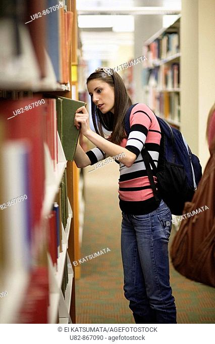 A young woman looking for a book in a library