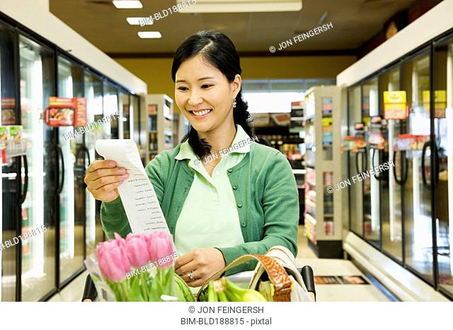 Asian woman reading list in grocery store