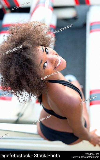 Portrait of beautiful afro american tourist woman enjoying her time on boat during her holiday in Europe. Very stylish woman in bikini