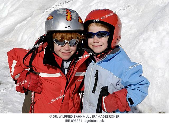 Two children wearing helmets for skiing