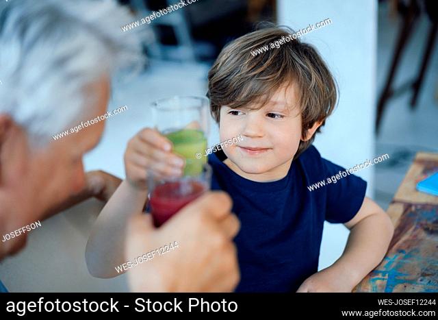 Grandson toasting juice with grandfather at home