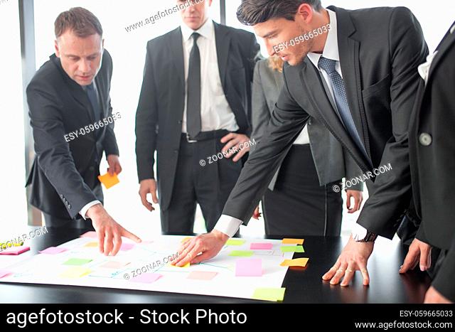 Business people team developing plan on office desk using stick notes