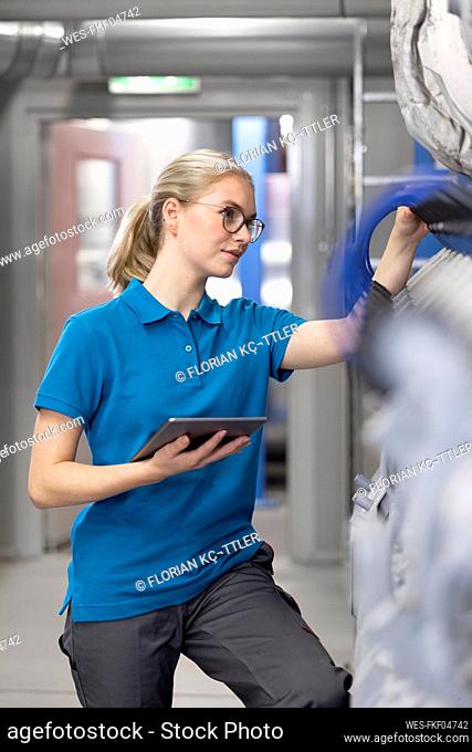 Technician analyzing machine through tablet PC in factory