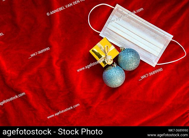 Christmas decoration sparkling baubles with gold gift box and protective face mask for Coronavirus, Covid-19 and Christmas holiday concept space for text red...