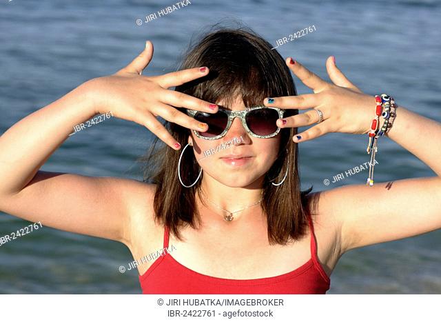 Girl, 12, wearing sunglasses and showing her colourful painted fingernails