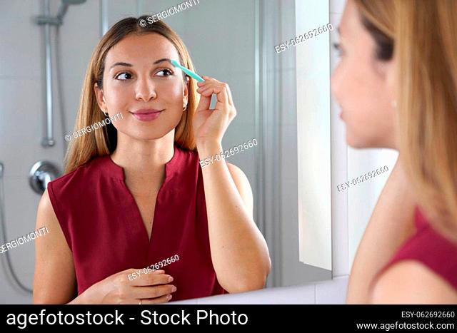 Pretty woman using razor on bathroom. Beautiful young woman shaving her face by razor at home