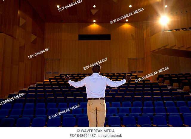 Businessman with arm stretched out standing in a auditorium