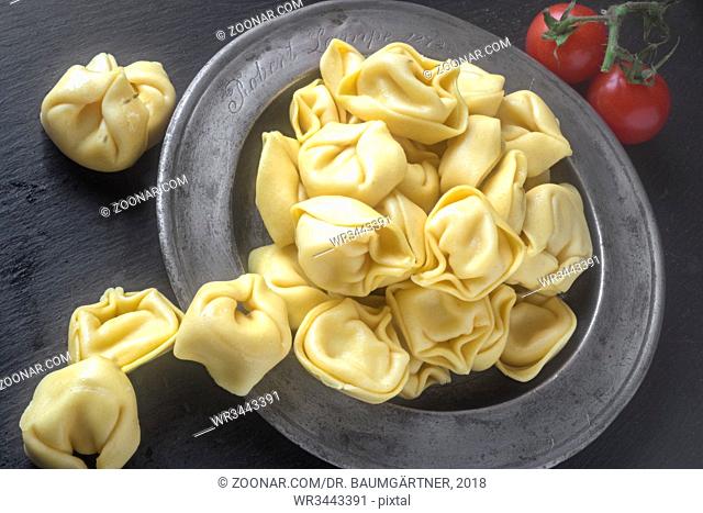 Frische Tortellini in einem Zinnteller. Fresh Tortellini, ring-shaped Italian pasta