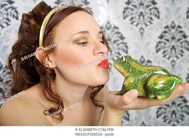 Portrait of young woman kissing frog