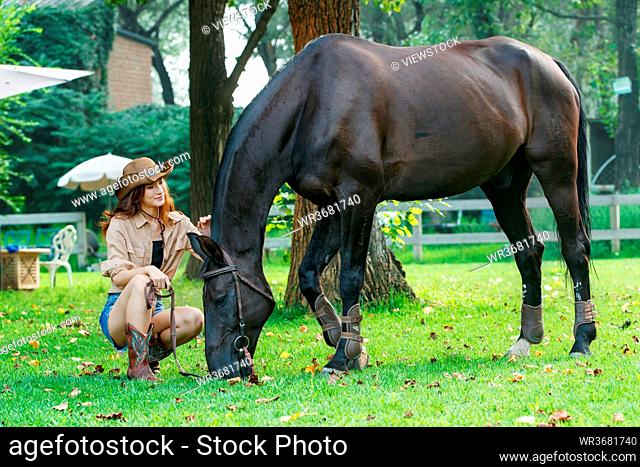 Outdoor young woman looked at the horse eat grass