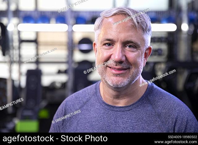 Portrait of fit senior man looking into camera smiling at gym