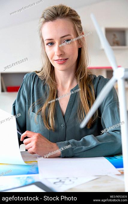 Woman at desk in office looking at wind turbine model