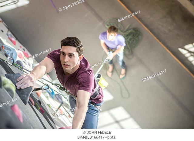 High angle view of athlete climbing rock wall in gym