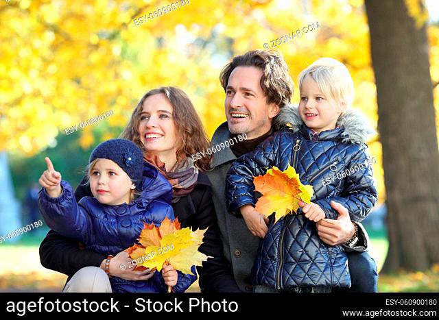 Portrait of happy family with autumn maple leaves in park