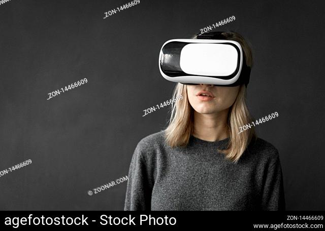Young woman wearing virtual reality goggles headset, vr box. Connection, technology, new generation, progress concept. Girl trying to touch objects in virtual...