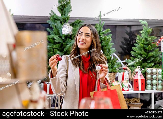 Thoughtful woman holding Christmas bauble in shop