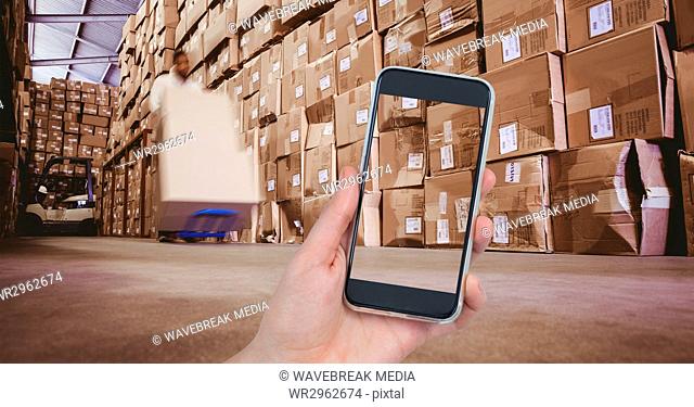 Hand photographing boxes in warehouse