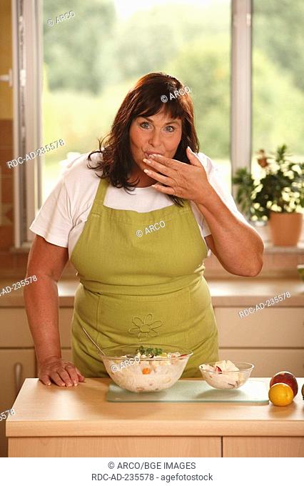Woman with bowl of fruit salad with yoghurt / testing, tasting