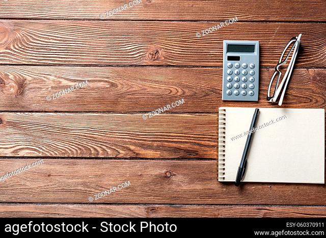 Still life of accountant vintage workspace with office accessories. Flat lay old hardwood desk with notepad, pen and calculator
