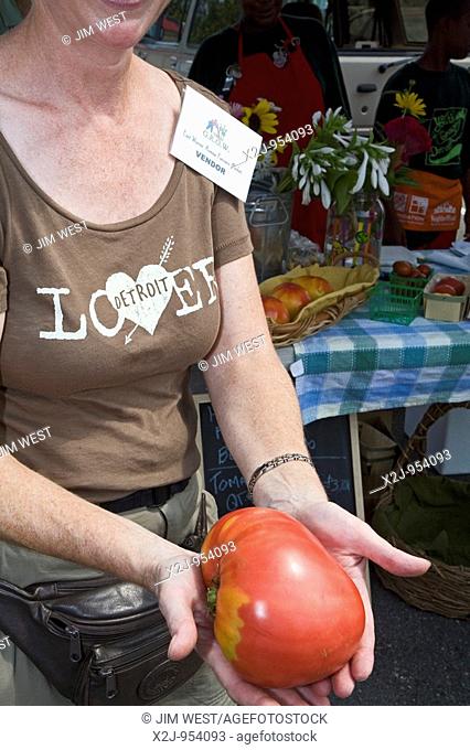 Detroit, Michigan - A vendor holds an heirloom tomato on sale at the East Warren Farmers Market, where everything is locally grown