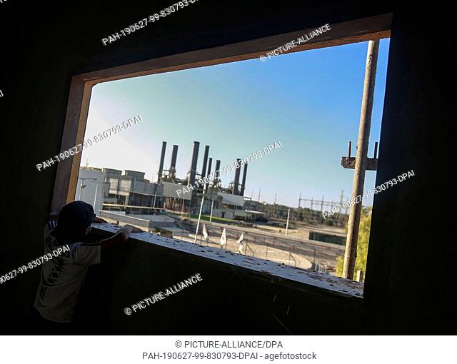 27 June 2019, Palestinian Territories, Gaza City: A child looks at the electricity generation plant in the central Gaza Strip