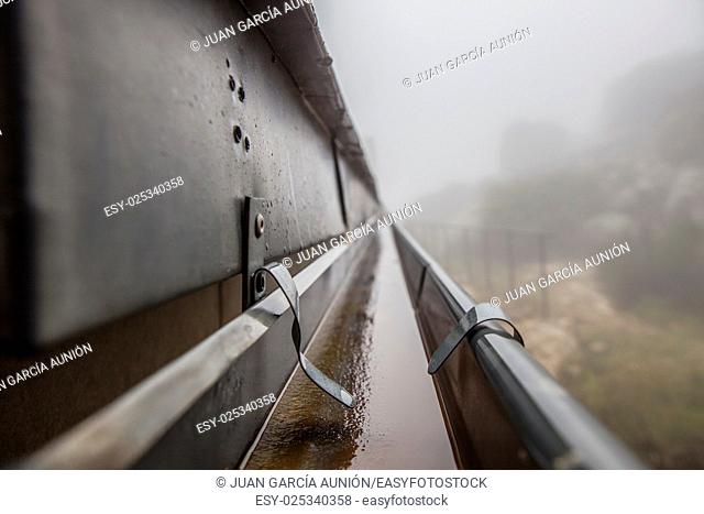 Gutter drainage system on the roof with dripping fog. Closeup
