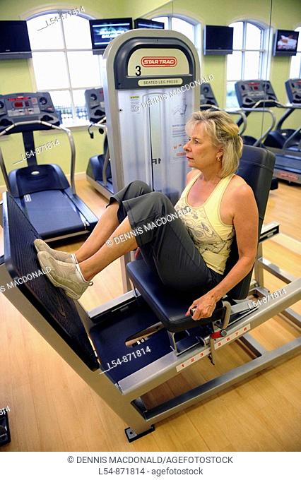 White woman on seated leg press machine in fitness center for glutes and quadriceps