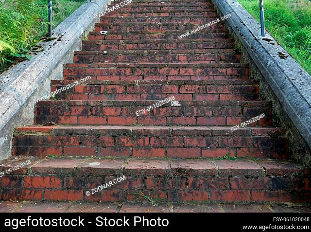 Old weathered brick staircase covered in moss with grass to side. High quality photo