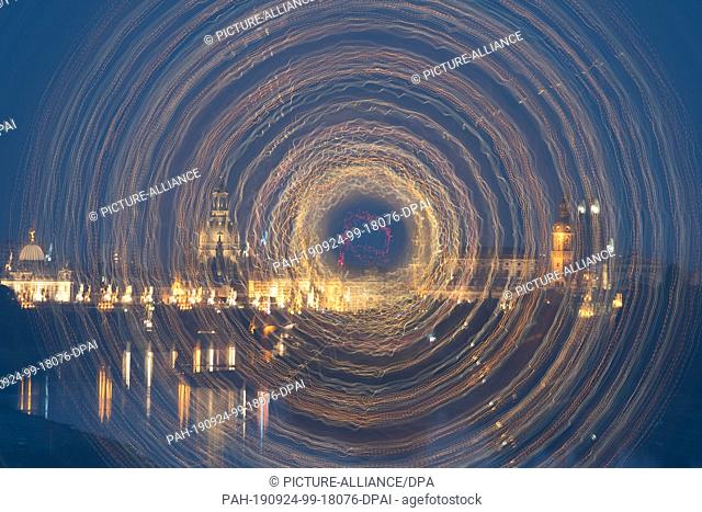 24 September 2019, Saxony: The scenery of Dresden's old town in front of the Elbe river is brightly illuminated at nightfall (long-term exposure and rotation...