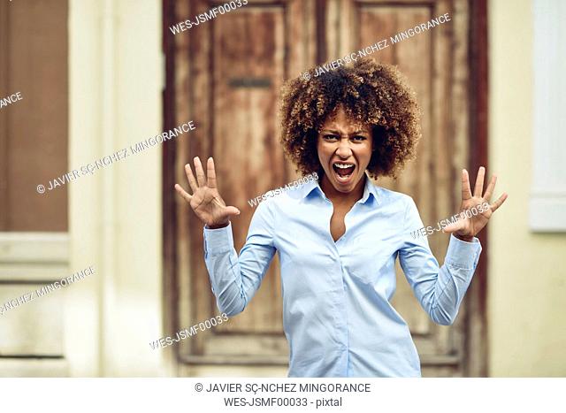 Portrait of woman with afro hairstyle screaming outdoors