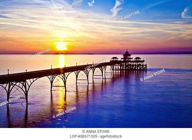 England, Somerset, Clevedon. The sun sets over the Bristol Channel behind the pier at Clevedon in Somerset