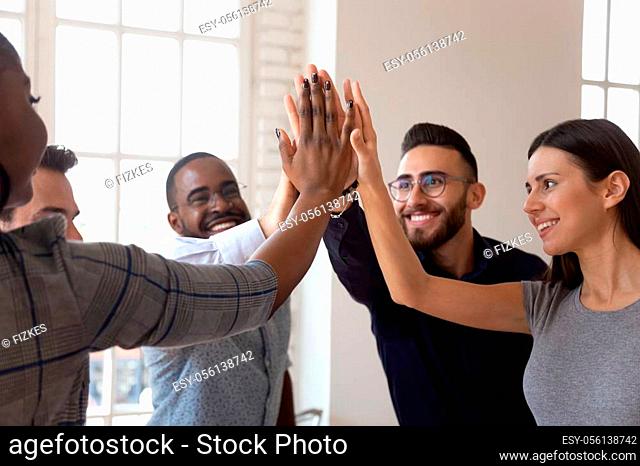 Head shot overjoyed multiracial young business team members giving high five, celebrating important company achievement or shared success