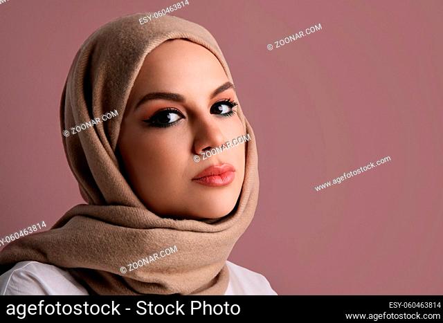 Young happy muslim woman wearing beige hijab. Isolated on the pink wall. High quality photo