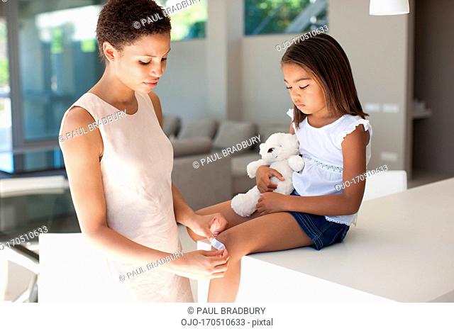 Mother putting bandage on daughter knee