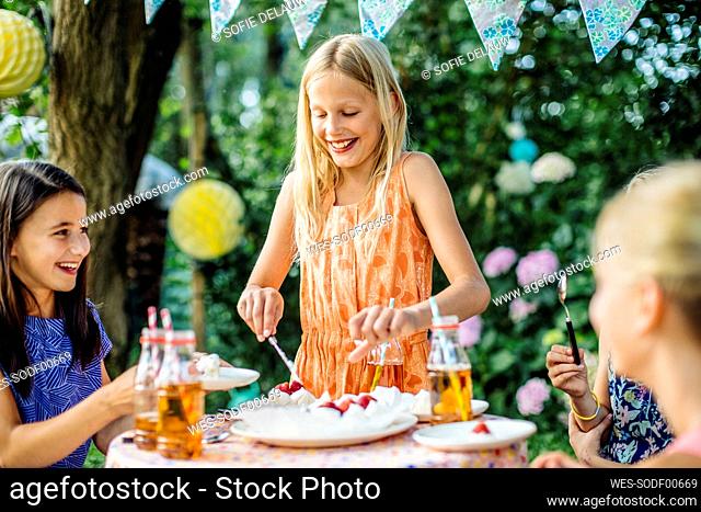Girl dishing up cake on a birthday party outdoors