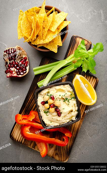 Flat lay view at vegetable Hummus dip dish topped with chickpeas and olive oil served with tortilla chips, celery and peppers