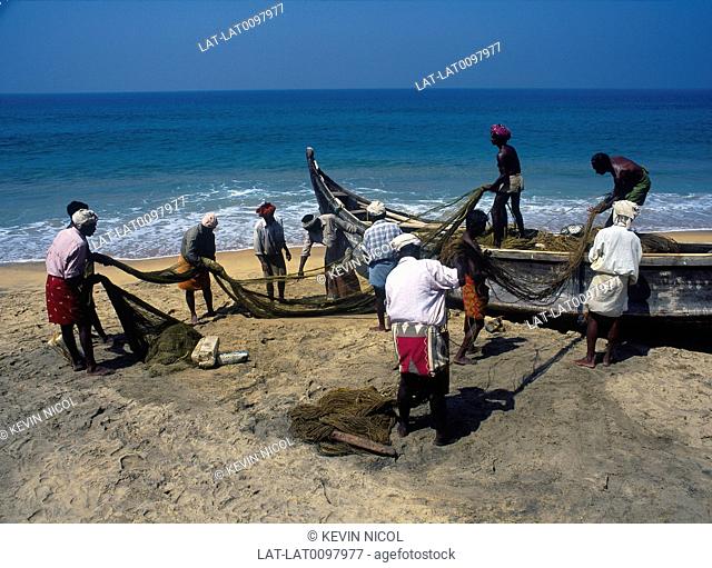 Kadaloram beach. Fisherman spreading nets to dry on sand. Dugout canoe boat